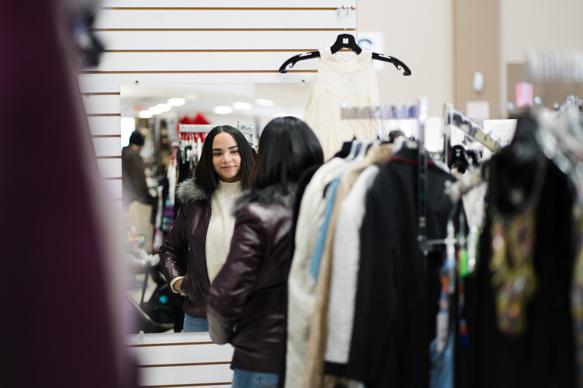 Marcela Morales tries on a stylish winter coat she found in the clothing section of the Calgary MCC Thrift Shop.
