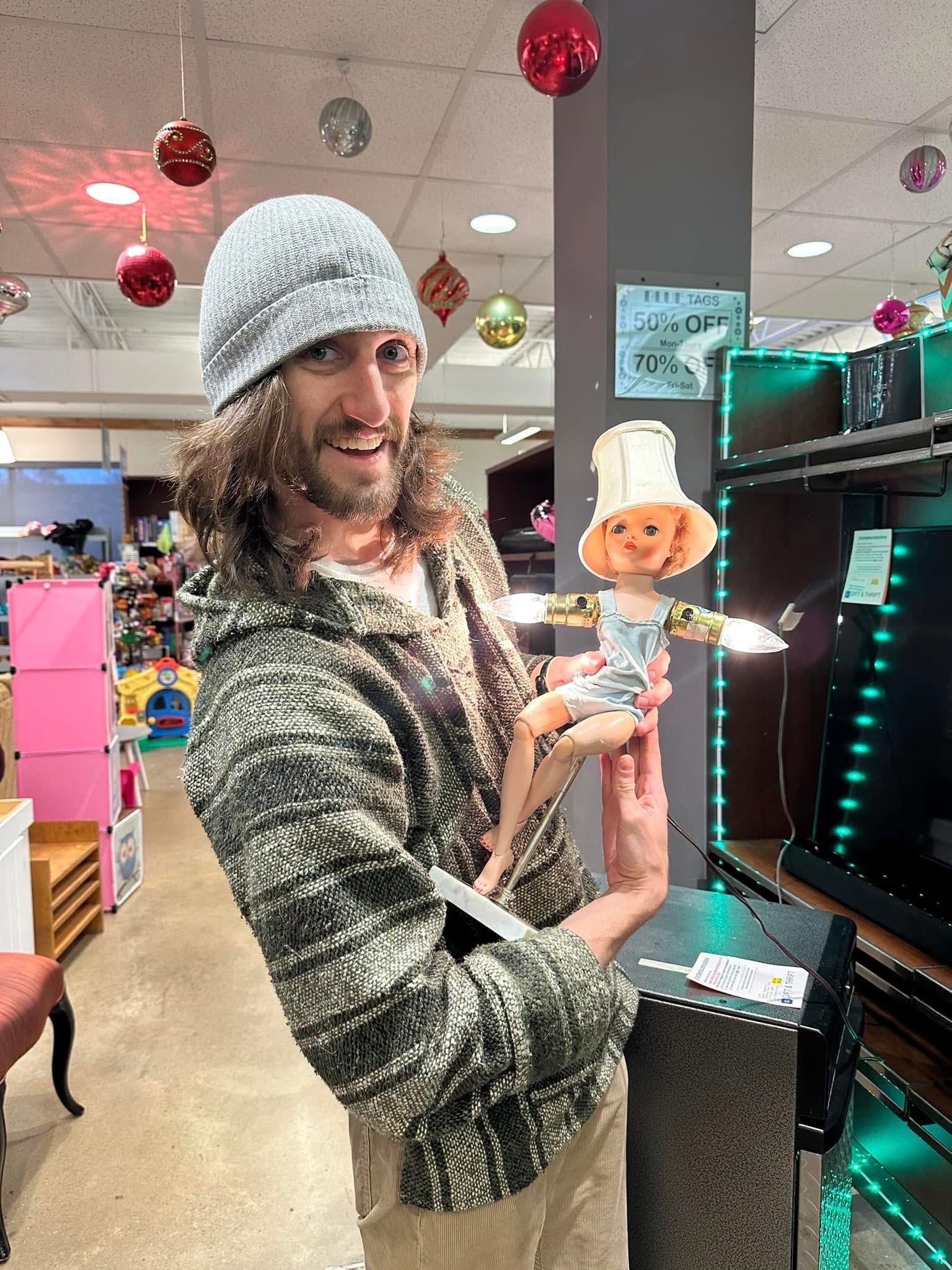 Volunteer holding a lamp made from a doll with lightbulbs for arms.