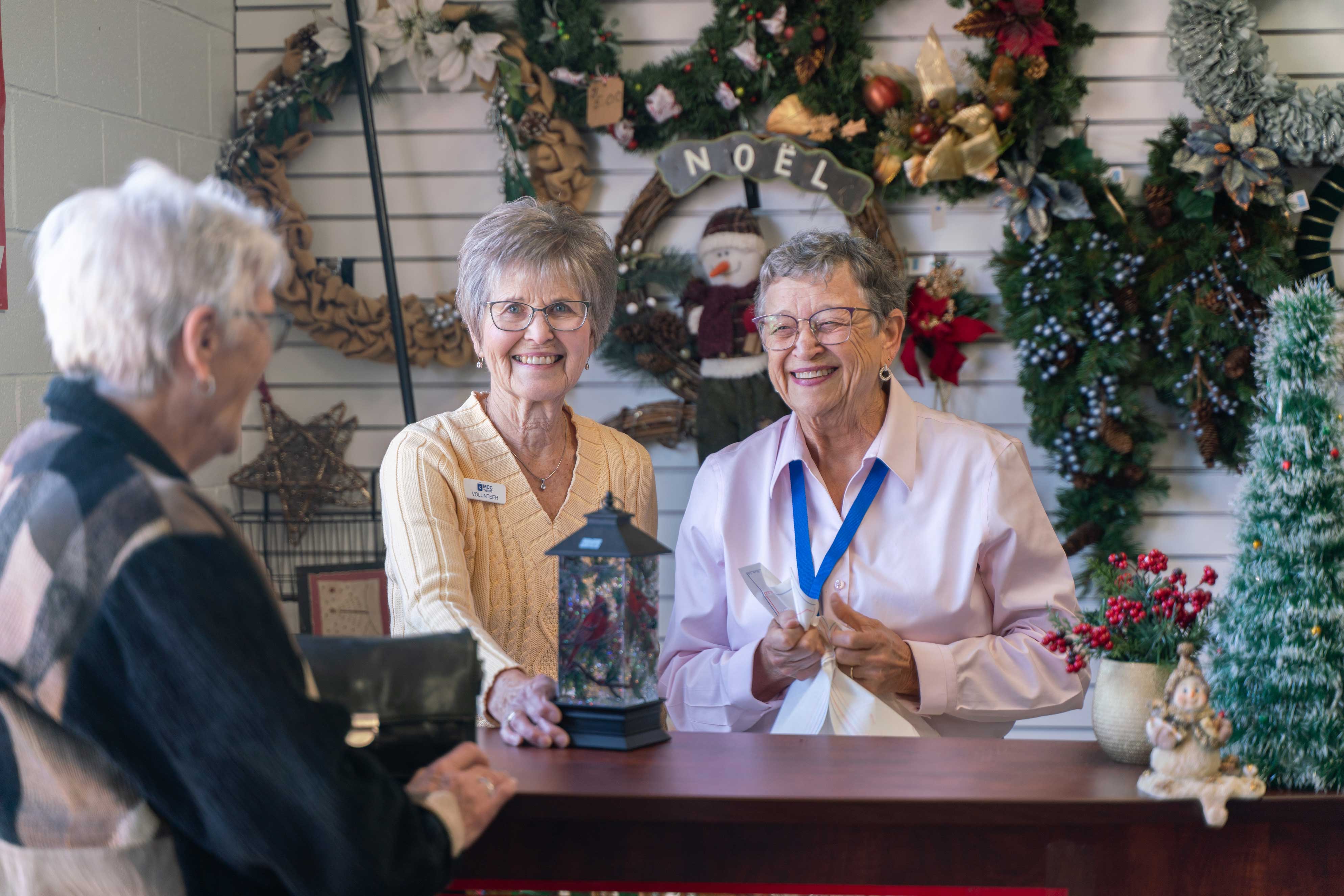 Volunteers help a customer at the checkout counter of the Christmas shop.