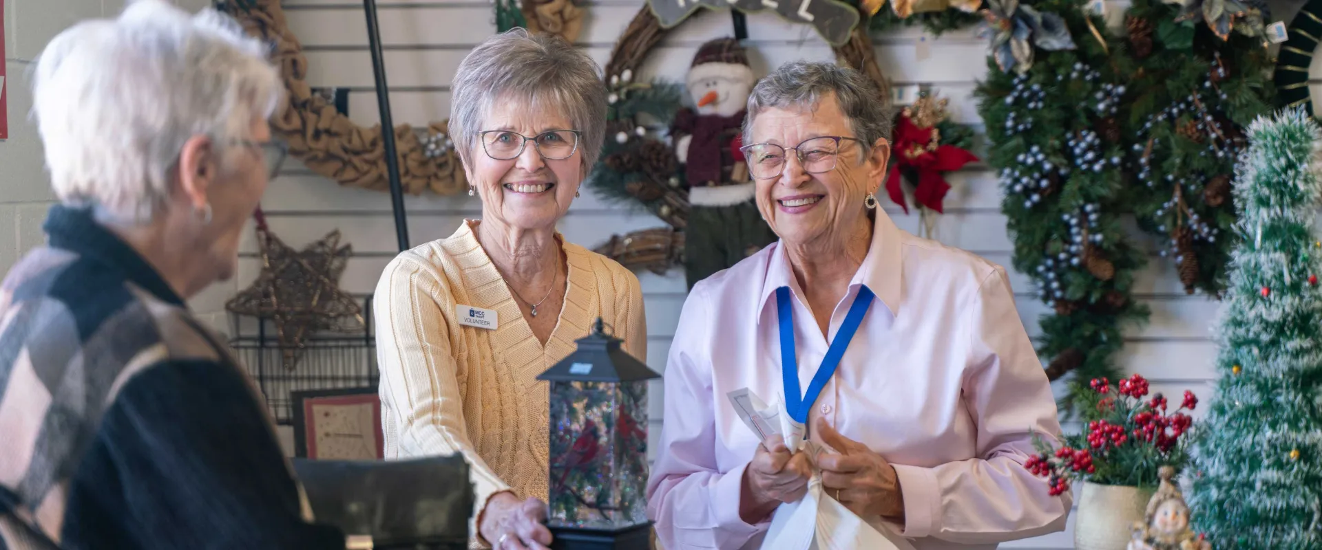 Volunteers help a customer at the checkout counter of the Christmas shop.