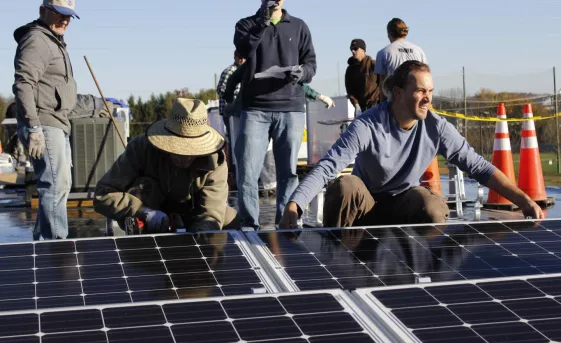 A group of volunteers lay solar panels on the rooftop of the Gift & Thrift MCC Thrift Shop in Harrisonburg,Virginia.
