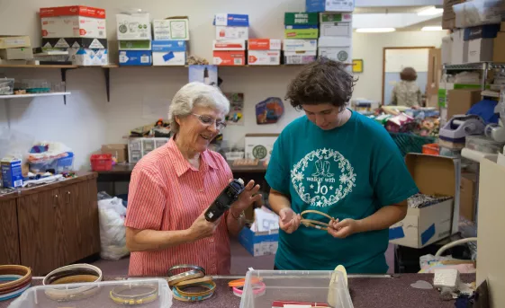 Two women volunteering with MCC Thrift, working with embroidery hoops.