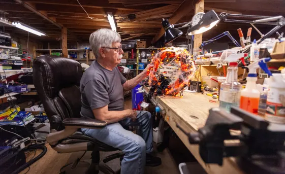 Older man volunteering by fixing damaged thrift items.