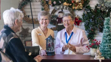 Volunteers help a customer at the checkout counter of the Christmas shop.